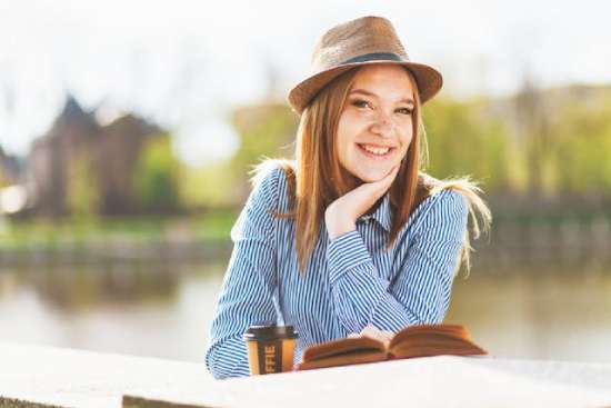 Woman smiling reading the bible A woman relaxing and reading the Bible by a lake on the Sabbath.