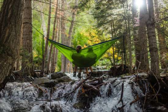 Two people relaxing in a hammock by a creek and enjoying Sabbath rest
