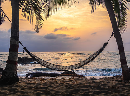 A hammock on a beach at sunset for enjoying a day of rest