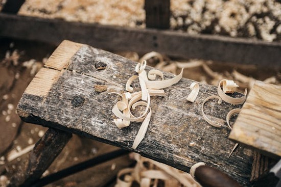 Wooden bench and shavings from carpentry A piece of rough lumber with wood shavings on top, representing Jesus' trade as a carpenter