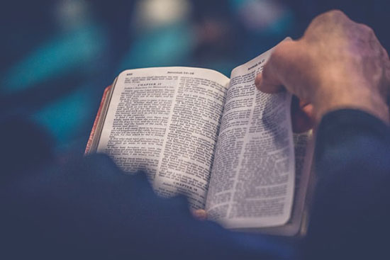 A man flips through pages in his Bible as he studies the subject of Jesus' divinity.