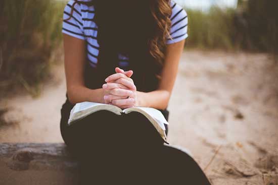 A girl reading a devotional and praying
