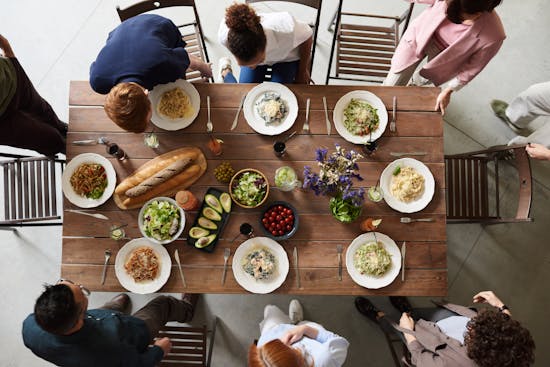 Group of friends eating together A group of friends gather around a wooden table with food. Sabbath is a great time to make connections while enjoying good food!