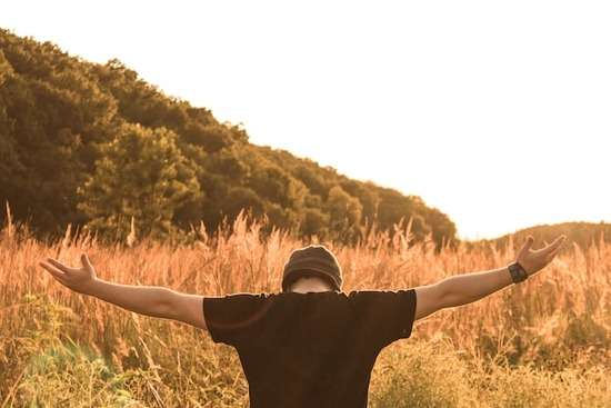 Man lifting up his hands in prayer as learn that lifting of hands in prayer is a sign of surrender and our need of God's hel