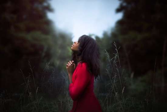 Woman praying in nature as we learn the importance of private prayers and time alone with God to pour our hearts to Him
