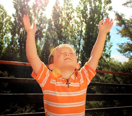 Child Lifting Hands Up A child looking up and lifting hands up in prayer