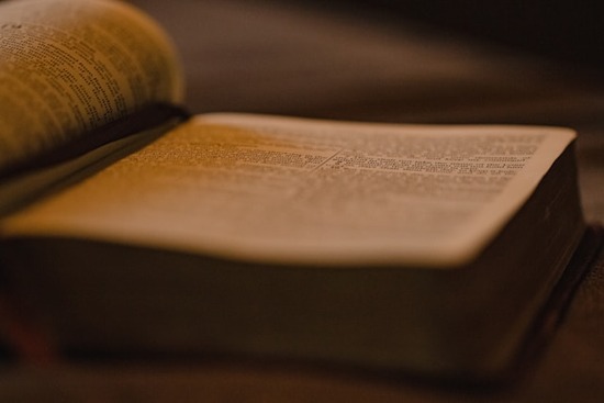 Bible open for studying An open Bible in a dimly lit setting.