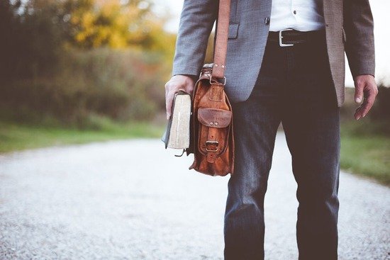 Man walking with Bible A man carries a leather satchel and Bible on his journey to spread the Gospel.