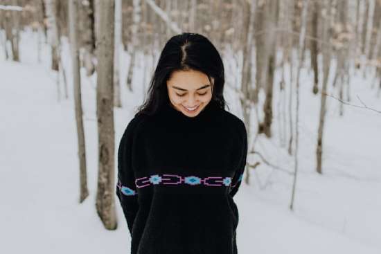 A humble woman, shy looking away from the camera, wearing modest clothing and jewelry
