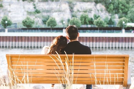 Couple on Bench Together Two young people sitting on a bench together