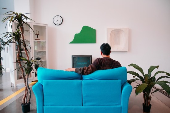 A man sitting on his sofa, flipping through channels on his T.V.