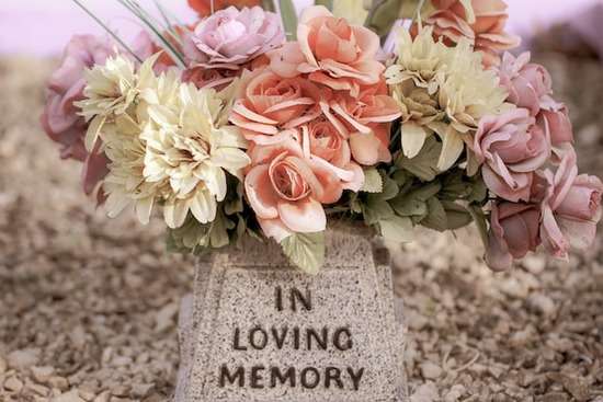 Flowers on a tombstone with the words In Loving Memory engraved on it