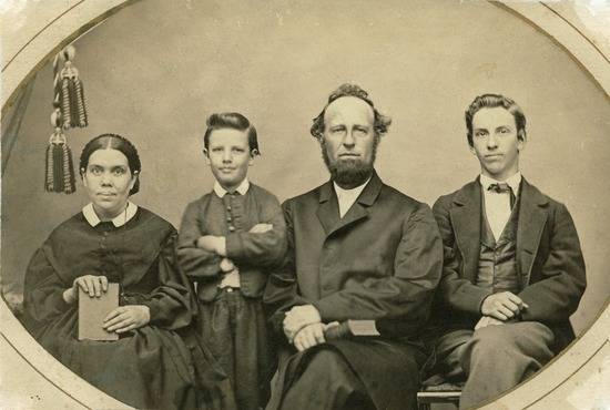 A photograph of Ellen White sitting by her two sons, Willie and Edmond, and her husband, James White.