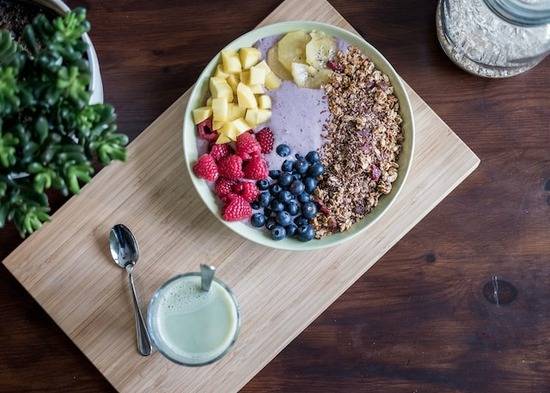 A smoothie bowl topped with fresh fruit and granola, a nutritious vegetarian breakfast.