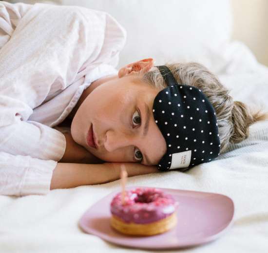 Woman Tempted with Donut A girl laying in bed and resisting the temptation to eat a donut on a plate in front of her