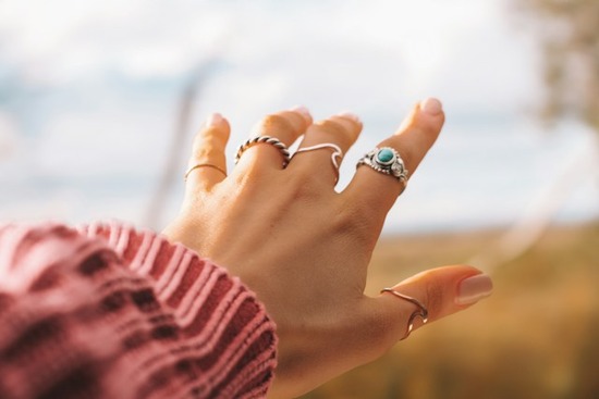 A young person's hand has simple rings on each of the five fingers.
