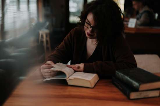 A woman studies the Bible at a wooden desk.