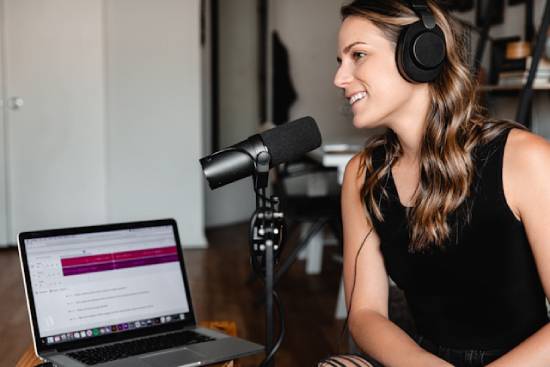 A woman with a laptop and microphone doing a podcast episode. Podcasts are one of many ways church members can serve and spread the Gospel!