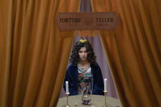 A woman sitting with a crystal ball and candles, depicting an example of fortune-telling.