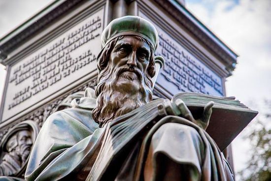 Bible opened in Genesis A sculpture of John Wycliffe reading the Bible