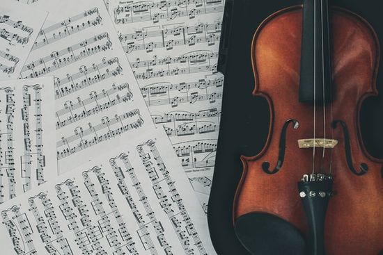 A violin laid next to scattered sheet music A violin laid next to scattered sheet music