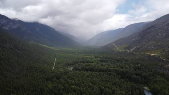 Clouds create mist over a mountain range that has a forested valley.