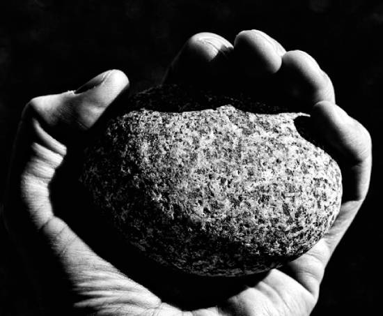 A close up of a hand holding a large stone.