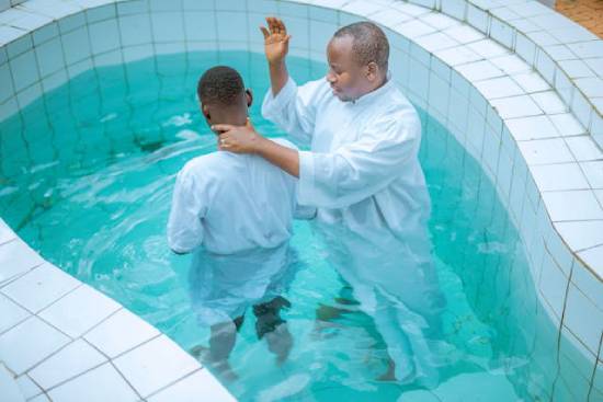 A pastor prepares to baptize a young man in a pool, demonstrating the biblical concept of baptism by immersion.
