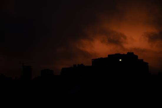  A home in the distance against a dark, ominous sky shows one lit window.