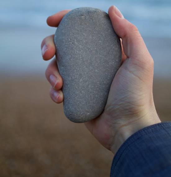 a person holds up a large, smooth stone in their hand