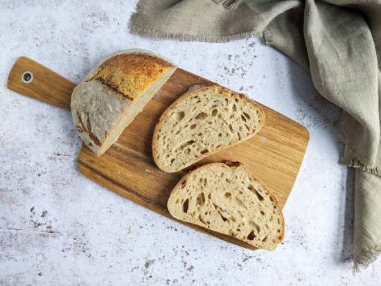 A fresh loaf of bread has a couple of slices cut off from it on a cutting board, symbolizing Jesus as spiritual nourishment.