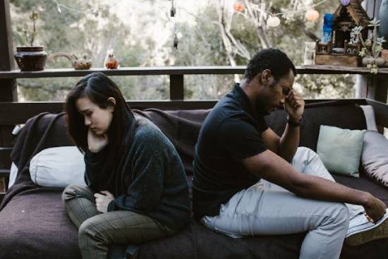 A young couple sits back-to-back as they deal with the difficulties of their relationship.