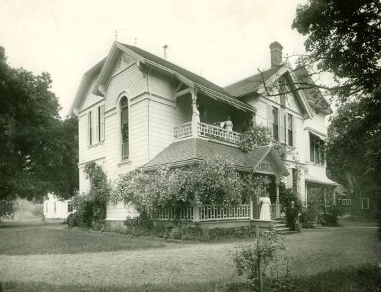 Ellen White at Elmshaven in St. Helena, California A black and white photo of Ellen g. White standing on the porch of a home in Elmshaven, St. Helena, California.