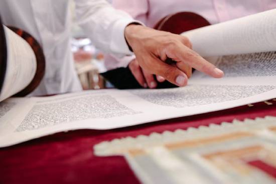 A man points at words on a scroll containing the Torah, illustrating how the lawyer in Jesus' day was a teacher of Old Testament laws.