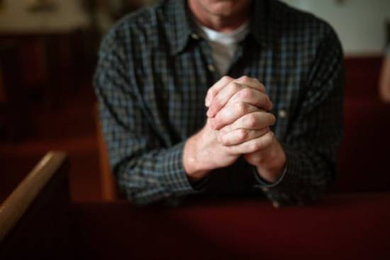 A man praying for the Holy Spirit A man prays with his hands clasped together, illustrating how prayer can be an example of