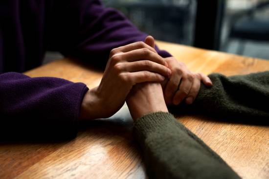 Two people grasp hands across a table.