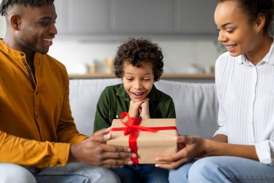 Parents giving their child a gift a couple surprises their young son with a wrapped gift
