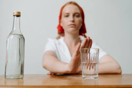 A woman holding up her hand to refuse a glass of alcohol