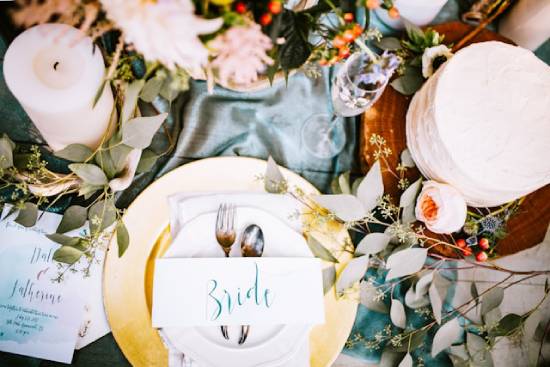 Decorated table setting with a nametag that says "Bride" An overhead shot of the bride's seat at a decorated table, complete with candles, flowers, fancy silverware, and an empty champagne glass.