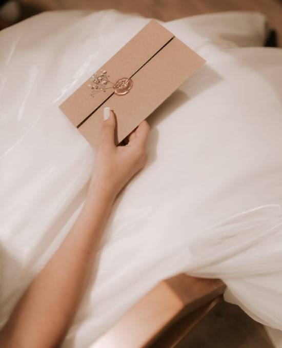 Bride holding a wedding invitation A bride sits in her wedding dress holding a sealed wedding invitation