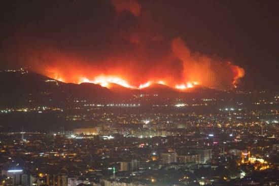 City with a wildfire burning in the background A wildfire in the background blazes the edges of a city in the foreground