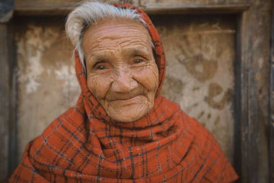 Elderly widow wearing red shawl An elderly woman of color wearing a red scarf smiles at the camera.