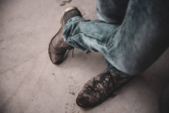 Man wearing jeans instead of proper wedding clothes Legs clothed in jeans and boots stand crossed at the knee