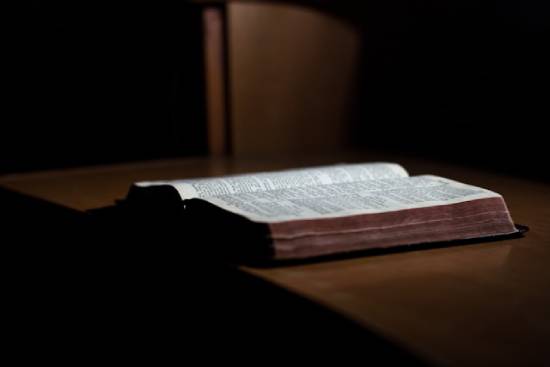 An open Bible sits on a wooden table.