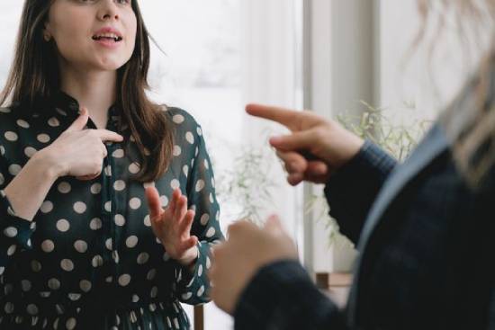  Two young women argue in an accusatory manner.