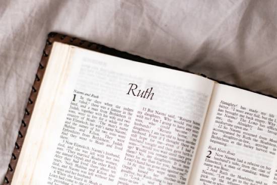 A Bible is opened to the first page of the Book of Ruth.