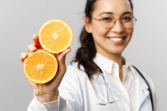 Female doctor holding up two sliced orange halves A doctor holding up an orange that's been split in half